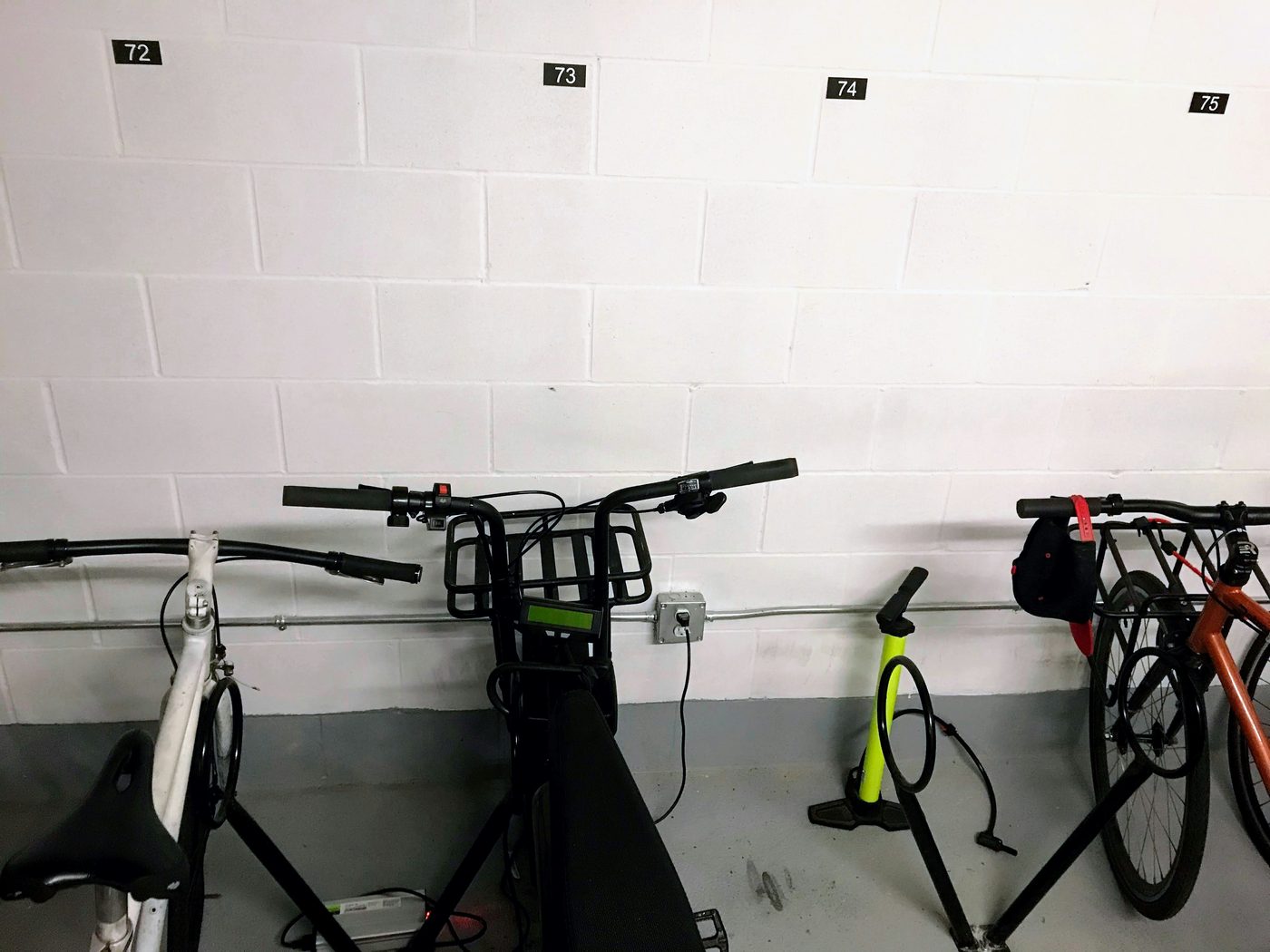 Indoor numbered bike-room parking with a pump and shared storage setup