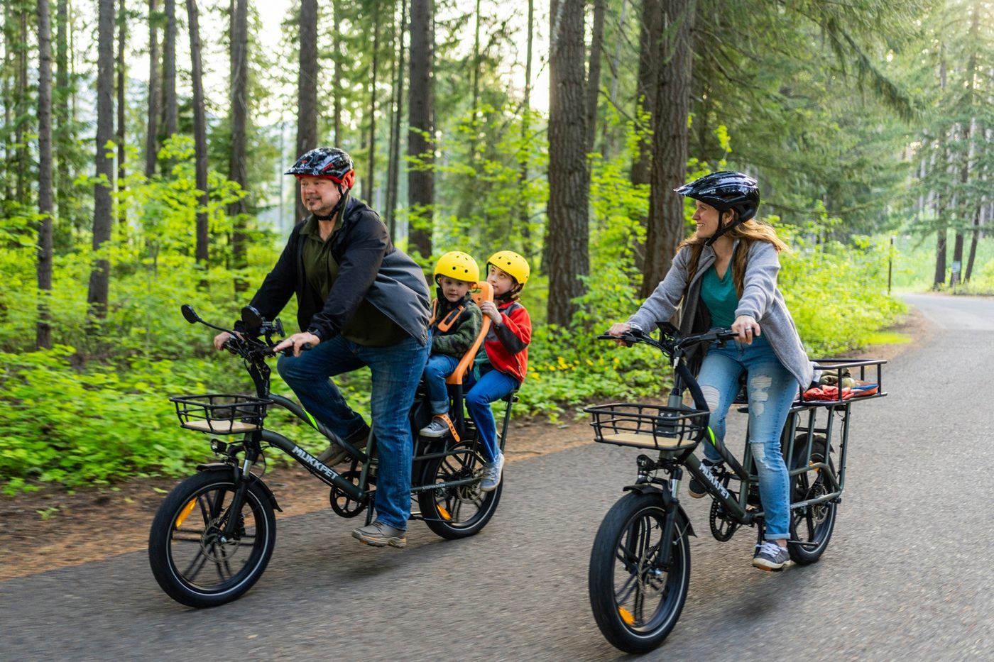 Family riding cargo e-bikes with kids on a road