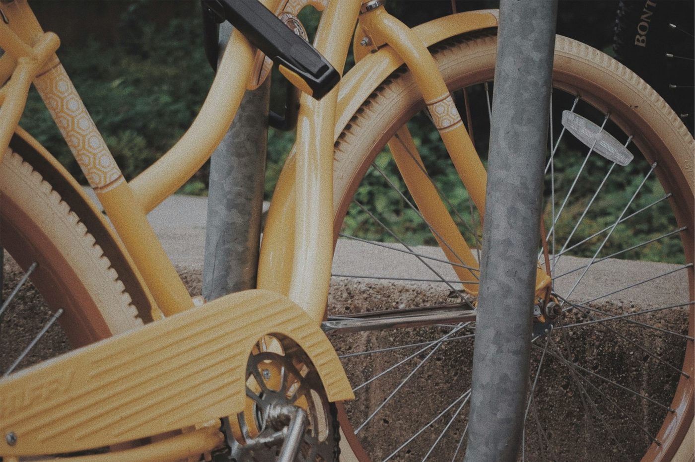Close-up of a bike parked beside a public metal post